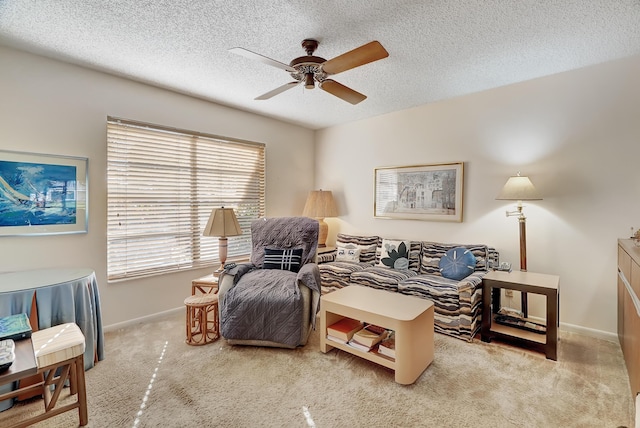 sitting room with ceiling fan, light carpet, and a textured ceiling