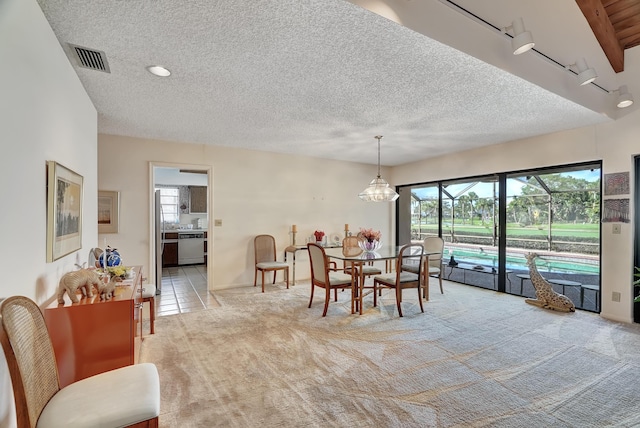 dining area featuring light colored carpet, a chandelier, and a textured ceiling