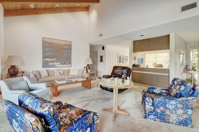 carpeted living room featuring beamed ceiling and wooden ceiling