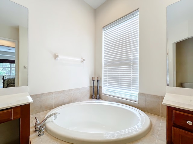 bathroom with vanity, tiled bath, and toilet