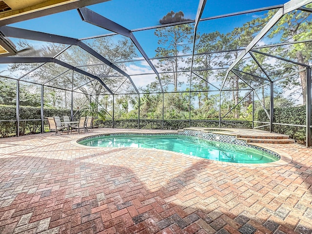 view of swimming pool with a patio area, an in ground hot tub, and glass enclosure