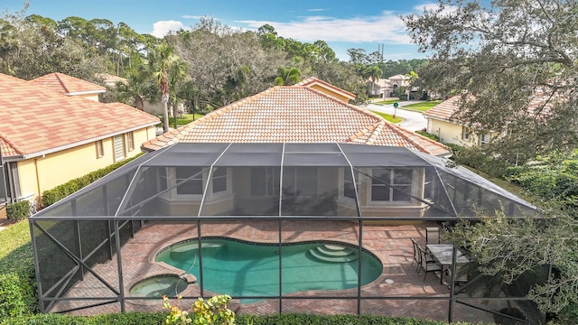 rear view of house featuring a swimming pool with hot tub, a patio, and glass enclosure