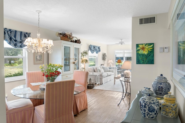 dining space featuring wood-type flooring, plenty of natural light, a notable chandelier, and a textured ceiling