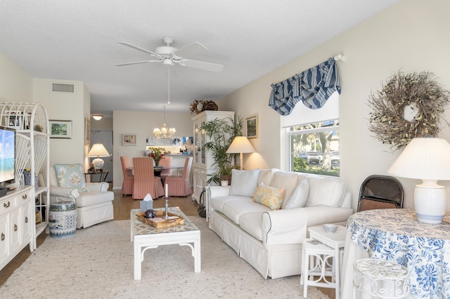 living room with ceiling fan with notable chandelier and a textured ceiling