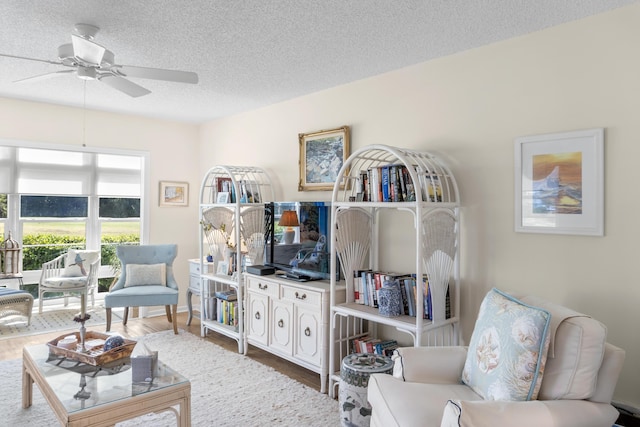 living room featuring hardwood / wood-style flooring, ceiling fan, and a textured ceiling