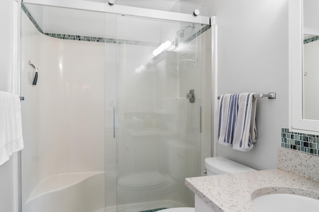 bathroom with tasteful backsplash, vanity, a shower with shower door, and toilet