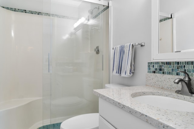 bathroom featuring tasteful backsplash, vanity, toilet, and walk in shower