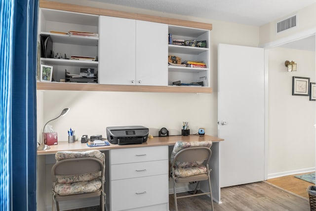 home office featuring built in desk and light wood-type flooring