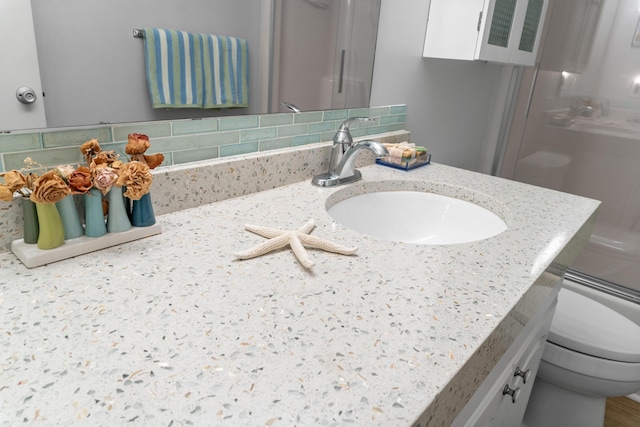 bathroom featuring vanity, decorative backsplash, and toilet