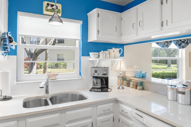 kitchen featuring pendant lighting, sink, dishwasher, white cabinetry, and a wealth of natural light