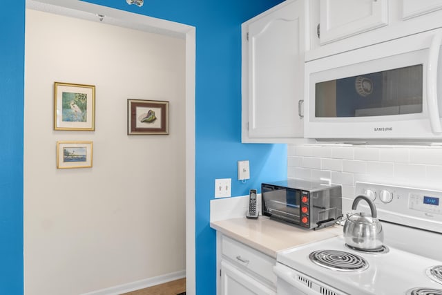 kitchen with white appliances, decorative backsplash, and white cabinets