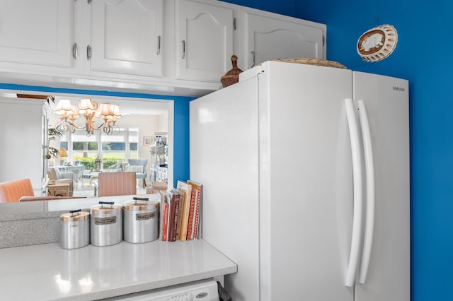 kitchen with white cabinetry, an inviting chandelier, and white fridge