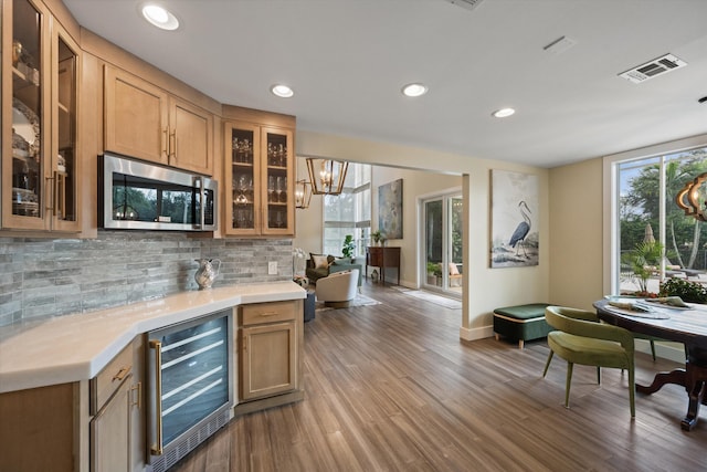 kitchen featuring a healthy amount of sunlight, wine cooler, light wood-type flooring, and decorative backsplash