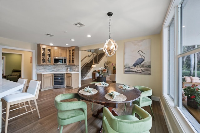 dining room with an inviting chandelier, dark wood-type flooring, beverage cooler, and bar