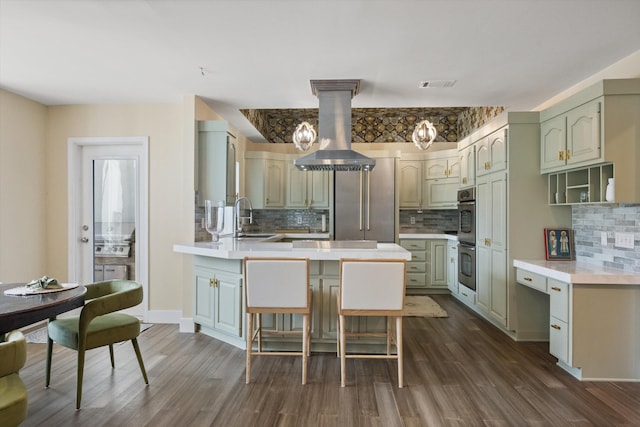 kitchen featuring a breakfast bar, sink, island range hood, dark hardwood / wood-style floors, and kitchen peninsula