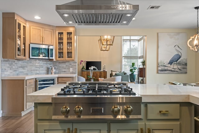 kitchen with green cabinetry, pendant lighting, island exhaust hood, stainless steel appliances, and decorative backsplash