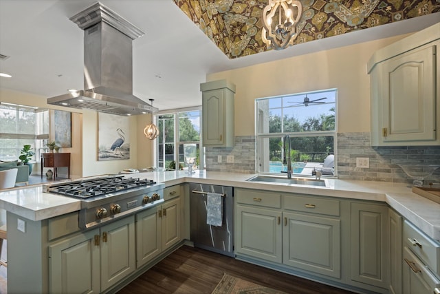 kitchen featuring appliances with stainless steel finishes, island range hood, pendant lighting, sink, and kitchen peninsula