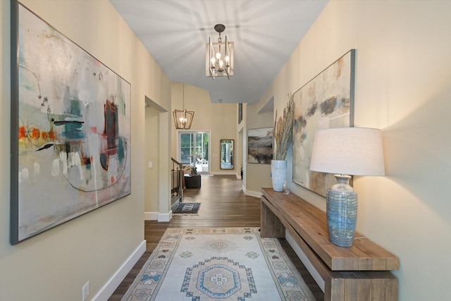 corridor with dark wood-type flooring and a chandelier