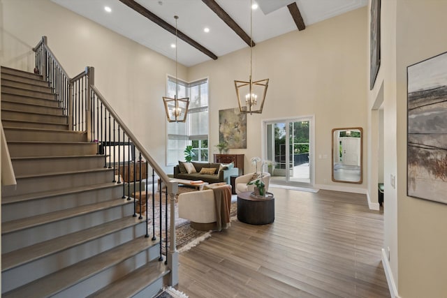 staircase featuring a high ceiling, hardwood / wood-style floors, a chandelier, and beam ceiling