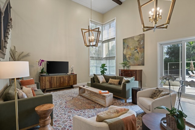 living room with a towering ceiling, a healthy amount of sunlight, and a notable chandelier