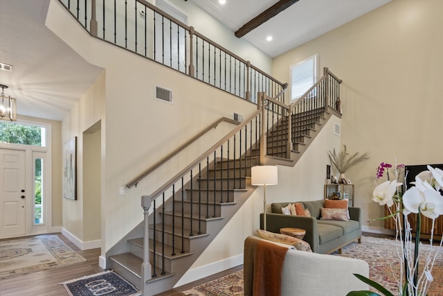 foyer entrance featuring beamed ceiling, plenty of natural light, a towering ceiling, and hardwood / wood-style floors