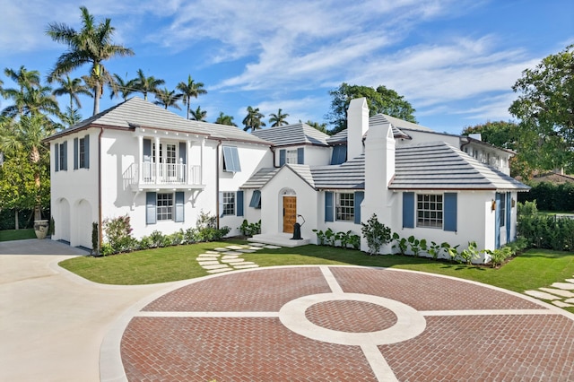 view of front facade featuring a garage, a balcony, and a front lawn