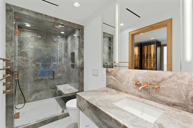 bathroom featuring vanity, toilet, a shower with shower door, and decorative backsplash