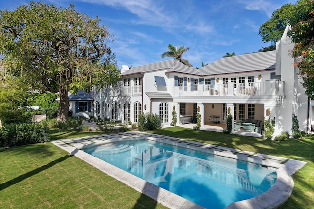 back of property with a yard, a patio area, outdoor lounge area, and a balcony