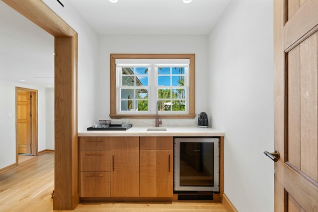 bar featuring sink, light hardwood / wood-style flooring, and beverage cooler