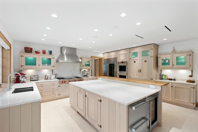 kitchen with sink, backsplash, stainless steel appliances, kitchen peninsula, and wall chimney exhaust hood