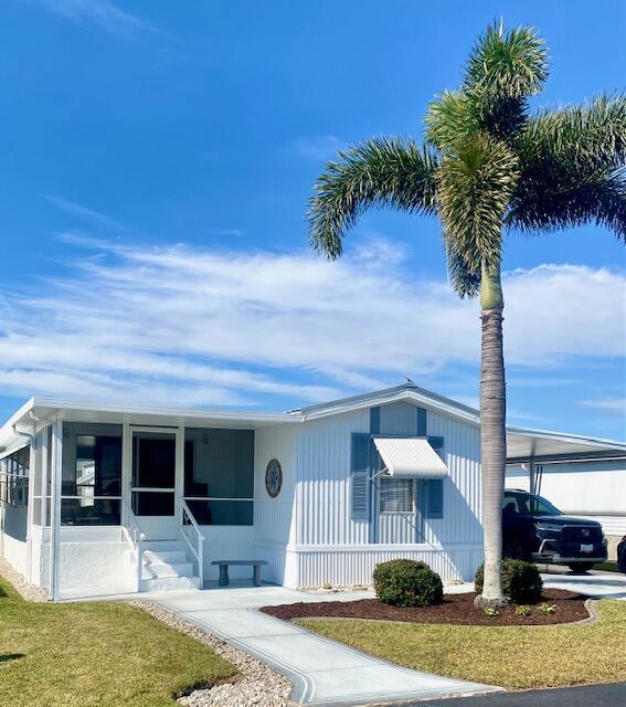 view of front of property with a front yard, a sunroom, and a carport