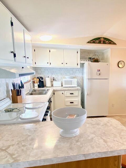 kitchen with tasteful backsplash, white appliances, sink, and white cabinets