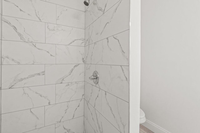 bathroom featuring tiled shower and toilet