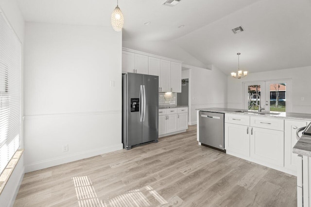 kitchen featuring appliances with stainless steel finishes, pendant lighting, white cabinetry, sink, and light hardwood / wood-style flooring