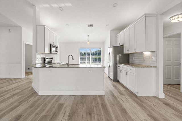 kitchen featuring stainless steel appliances, sink, hanging light fixtures, and white cabinets