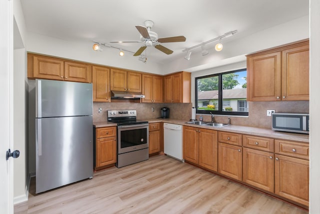 kitchen featuring appliances with stainless steel finishes, light hardwood / wood-style floors, sink, and backsplash