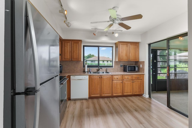 kitchen with sink, light hardwood / wood-style flooring, ceiling fan, stainless steel appliances, and tasteful backsplash