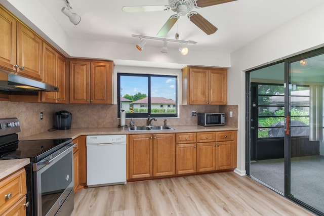 kitchen with sink, ceiling fan, stainless steel appliances, light hardwood / wood-style floors, and decorative backsplash