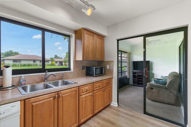 kitchen featuring light wood-type flooring, sink, white dishwasher, and decorative backsplash