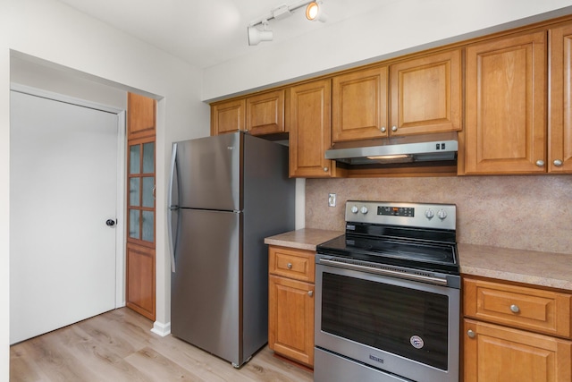 kitchen with tasteful backsplash, appliances with stainless steel finishes, and light hardwood / wood-style floors