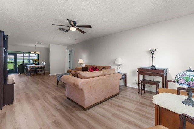 living room featuring ceiling fan with notable chandelier, a textured ceiling, and light wood-type flooring