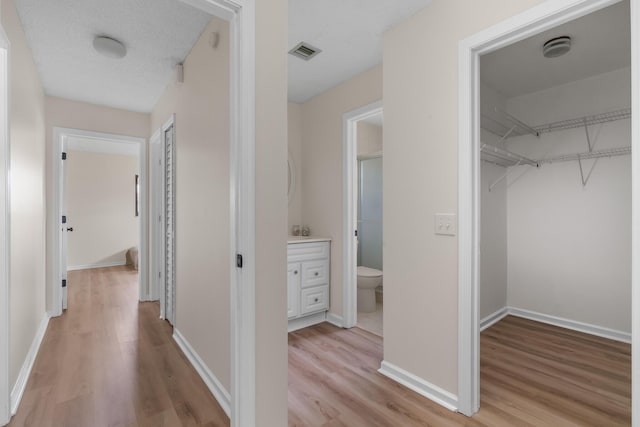 hallway with light hardwood / wood-style floors and a textured ceiling