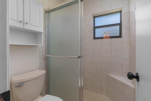 bathroom featuring a shower with door and toilet