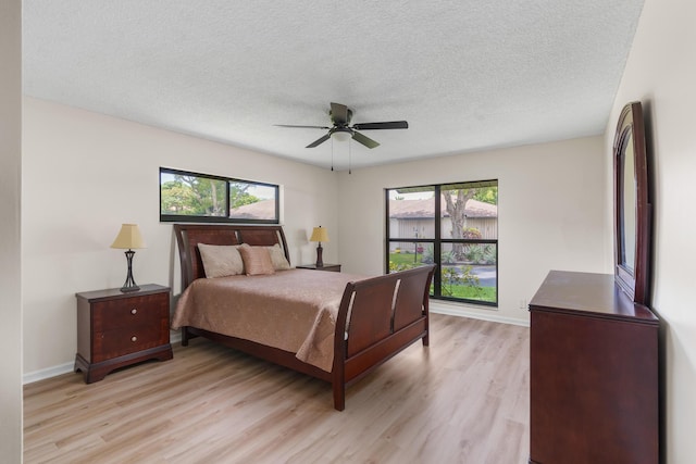 bedroom with multiple windows, a textured ceiling, and light wood-type flooring