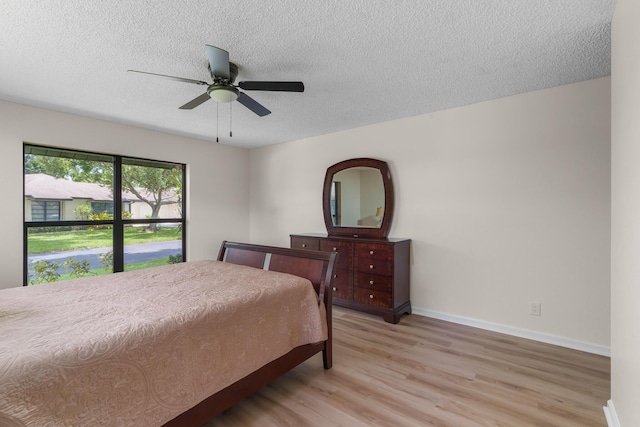 bedroom with ceiling fan, a textured ceiling, and light wood-type flooring