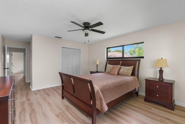 bedroom featuring a closet, ceiling fan, light hardwood / wood-style floors, and a textured ceiling