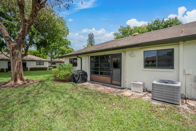 rear view of property featuring a yard and central AC