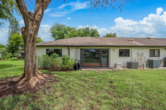 rear view of property with cooling unit and a lawn