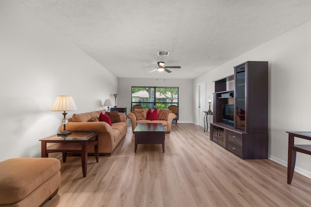 living room with ceiling fan, a textured ceiling, and light wood-type flooring