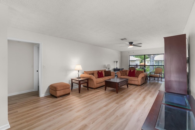 living room with ceiling fan, light hardwood / wood-style floors, and a textured ceiling